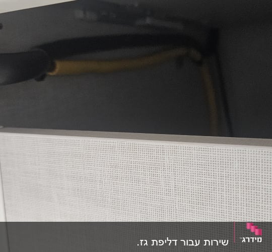 צינור שחור מחובר לקיר עם כבל צהוב
